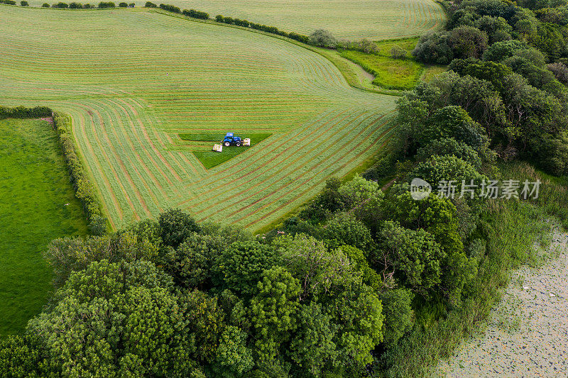 一辆拖拉机在苏格兰西南部邓弗里斯和加洛韦乡村的田野上割草。