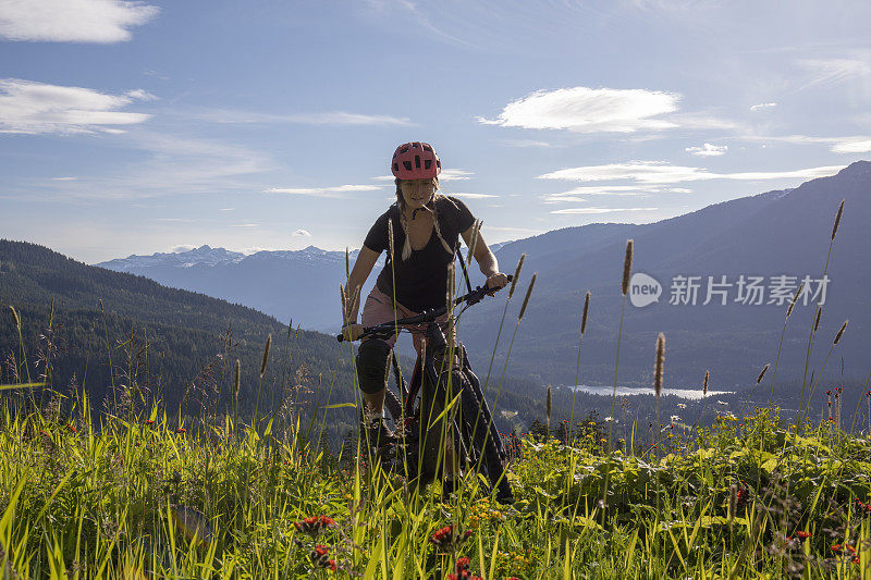 年轻女子骑山地车穿过山地草地