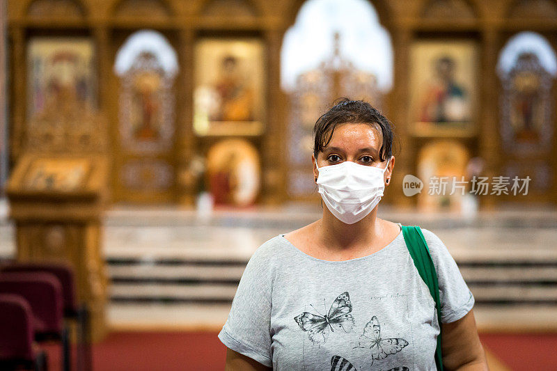 在教堂里祈祷的年轻妇女戴着防护面具