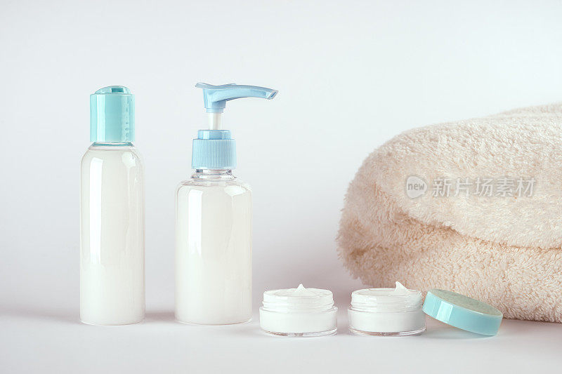 霜、洗液、凝胶、泡沫或护肤品的包装和一条毛巾在白色的背景上有拷贝空间。化妆品美容产品品牌模型
