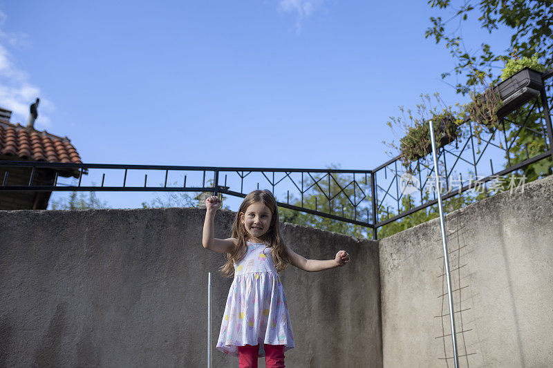 快乐的蹒跚学步的小女孩在外面蹦床上蹦蹦跳跳
