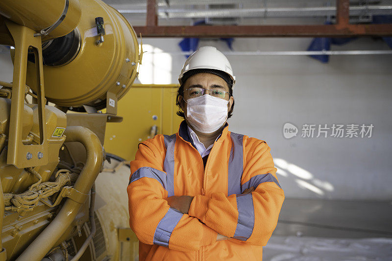值班的男工程师穿着防护服站在工厂使用的机器前微笑