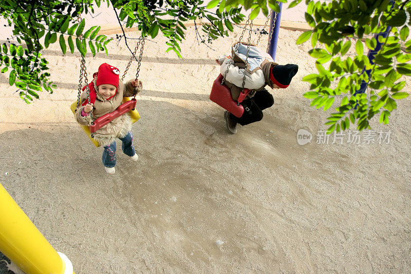 小学的弟弟和妹妹在儿童操场上玩秋千