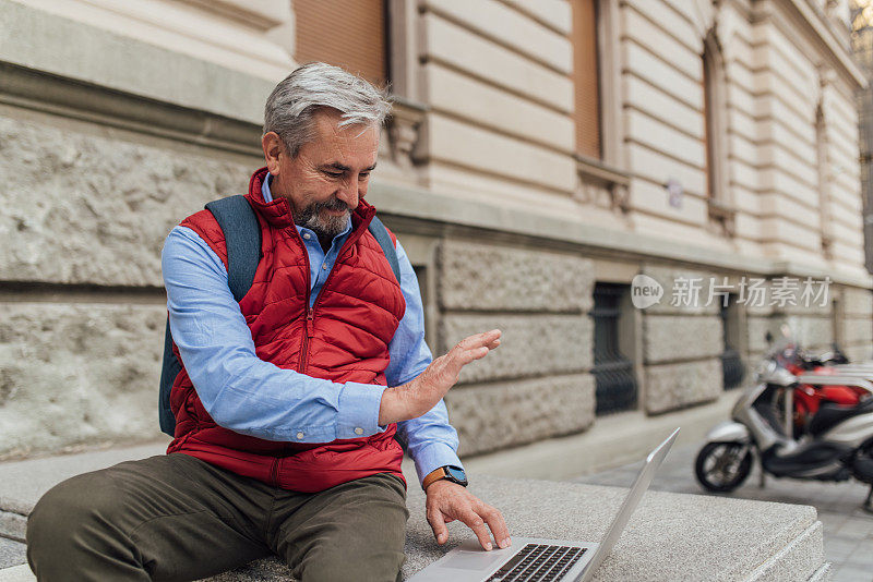 一个老人坐在街上打视频电话的照片