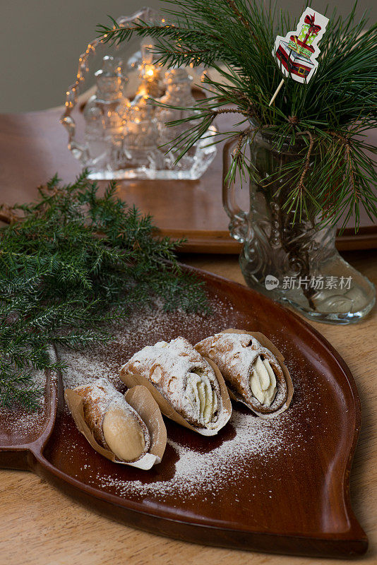 圣诞餐桌-糖霜粉落在奶油煎饼卷上，红木托盘装饰针叶树的树枝