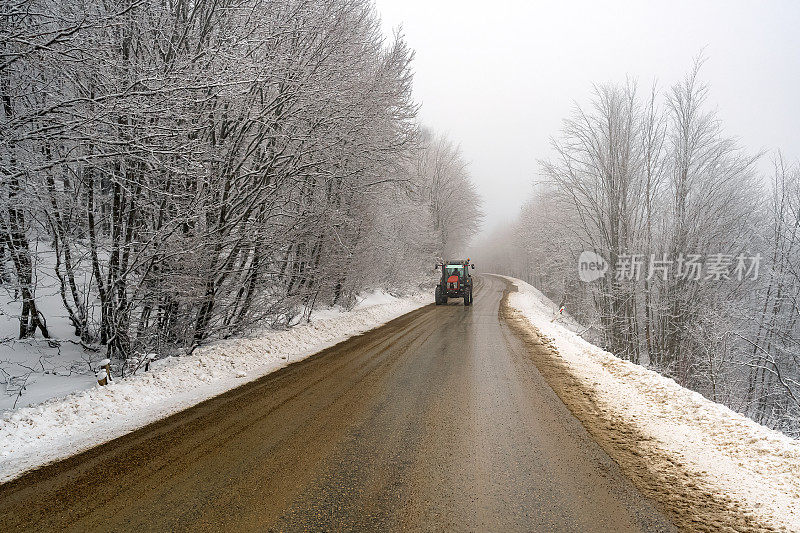 冬天，拖拉机在森林里的道路上行驶