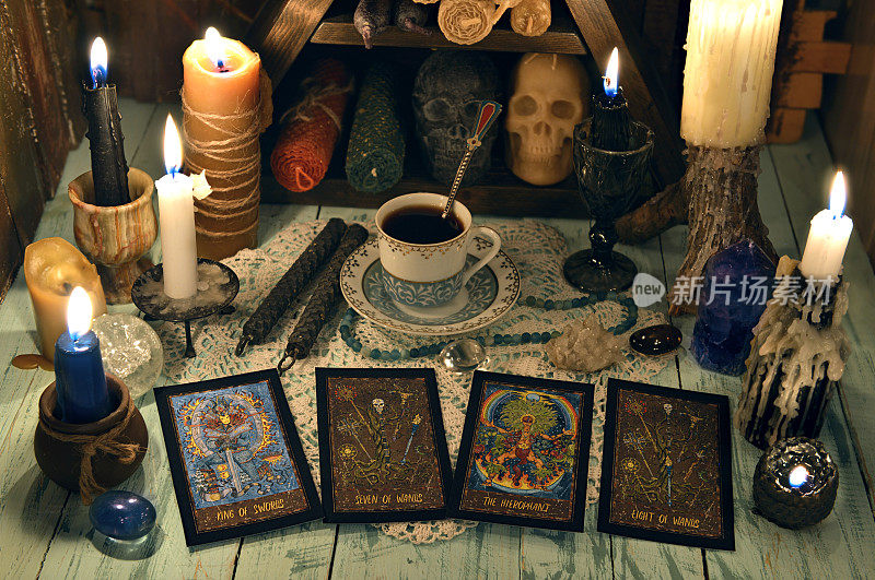 算命仪式与塔罗牌，燃烧的蜡烛，杯茶和水晶在木桌上。