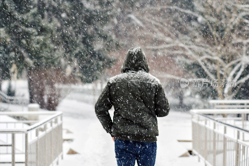 一个年轻人在下雪的天气在公园散步