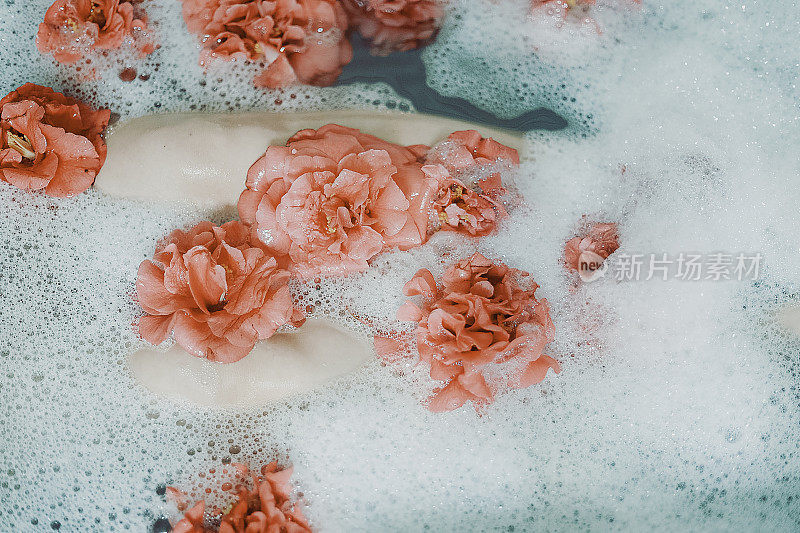 泡在泡泡和粉红玫瑰浴中的女性