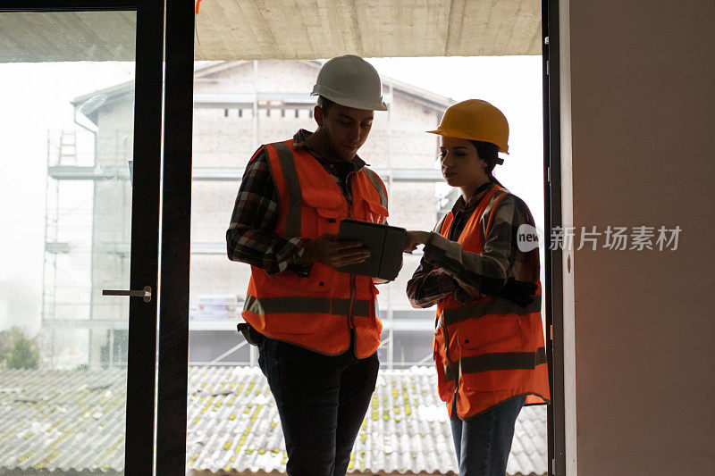 两名建筑师在一个正在施工的工地上使用数字平板电脑