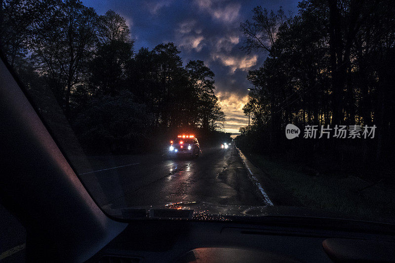 超速闪烁的紧急SUV救护车驶近下雨的乡村公路