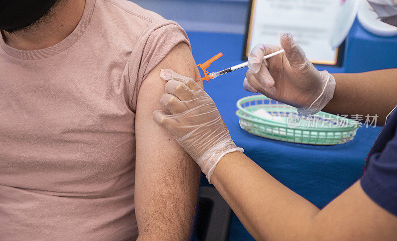 在卫生所的疫苗接种中心，护士用注射器给男子的手臂注射疫苗