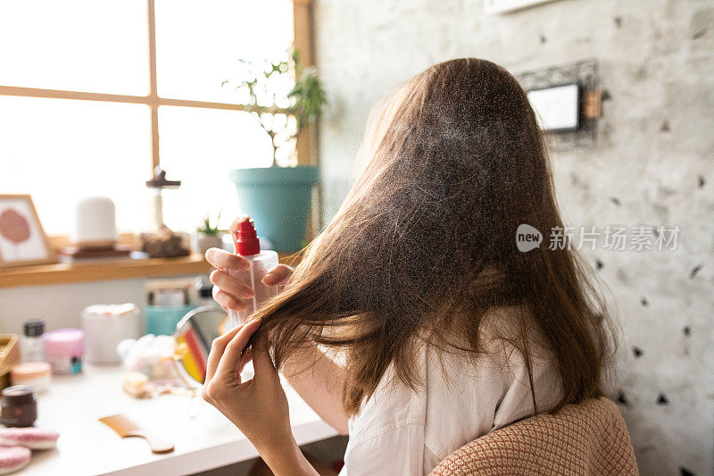 一名年轻女子清晨在卧室里喷发胶