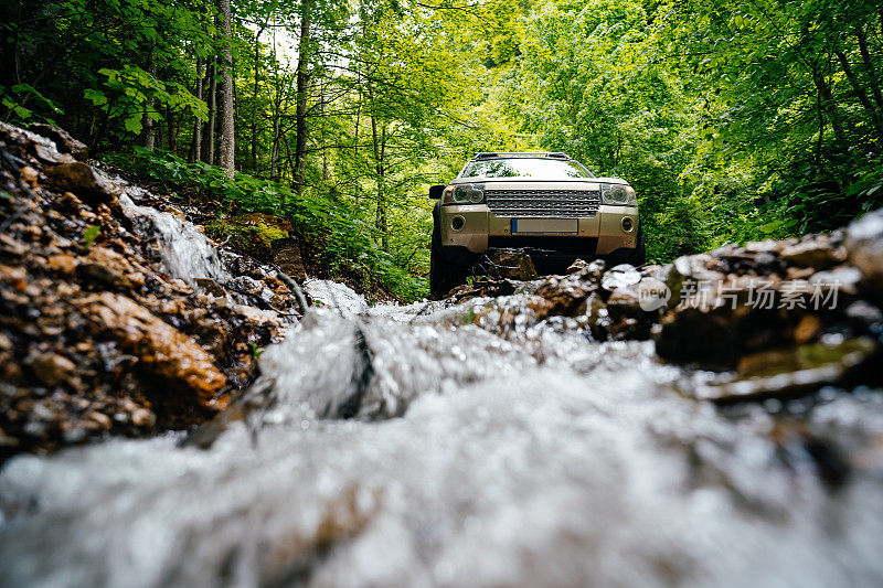 在森林里，越野车在溪流中穿过岩石