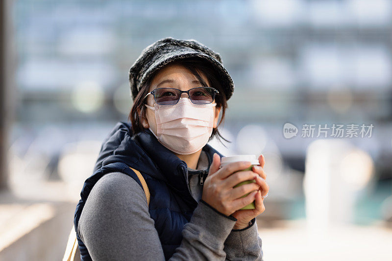 带着面罩和咖啡杯的女人在户外