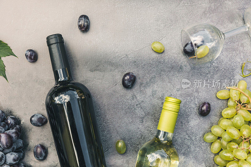 俯瞰瓶红和白葡萄酒，绿藤，葡萄酒杯和成熟的葡萄在年份黑石桌子背景。酒店酒吧酒庄或品酒的概念