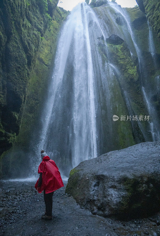 游客在瀑布Gljúfrabúi，就像在一个巨大的岩石后面的洞穴，冰岛