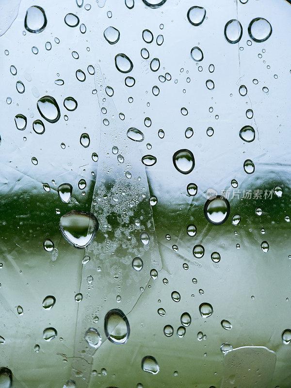 雨滴落在窗户上，模糊了背景中的风景