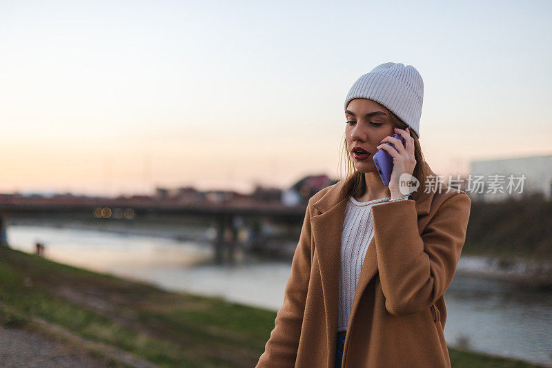 年轻漂亮的女人穿着外套，用手机聊天