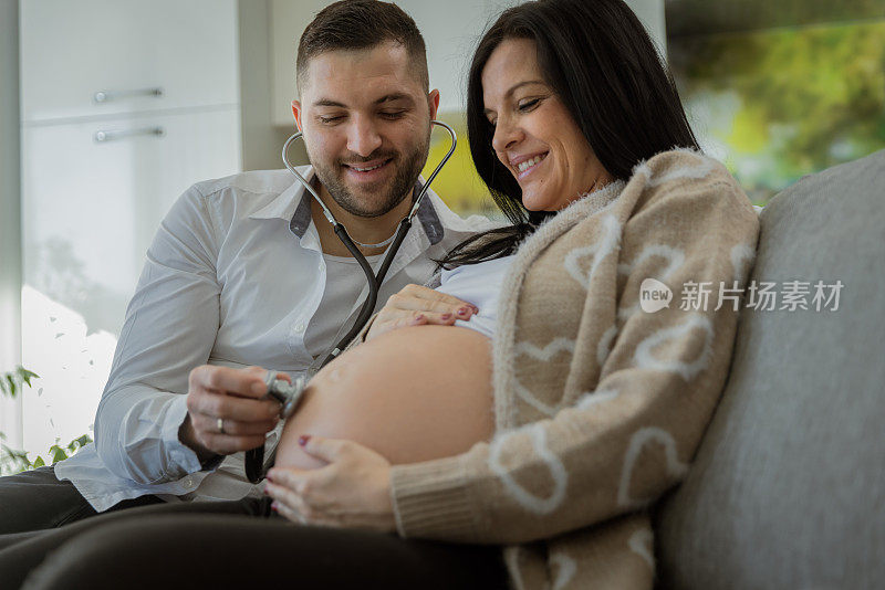 男人用听诊器在他怀孕妻子的肚子上听婴儿的心跳