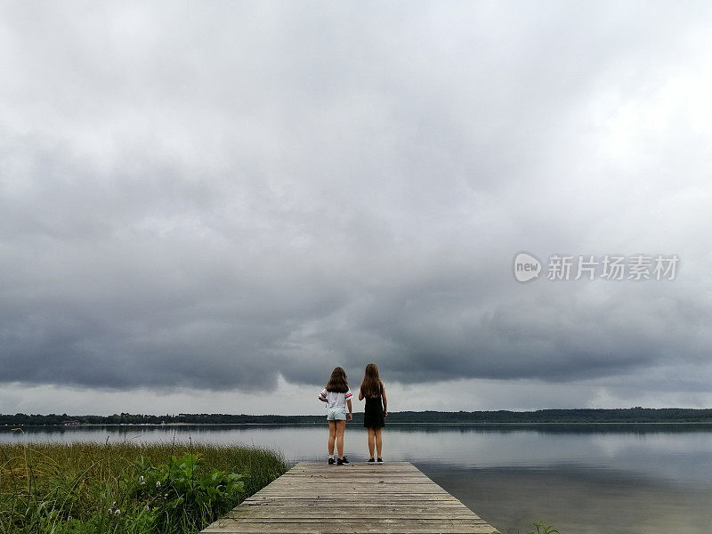两个女孩在阴天站在湖边