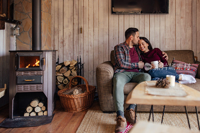 一对情侣在一起享受，在恋爱，在室内，在壁炉旁喝咖啡。