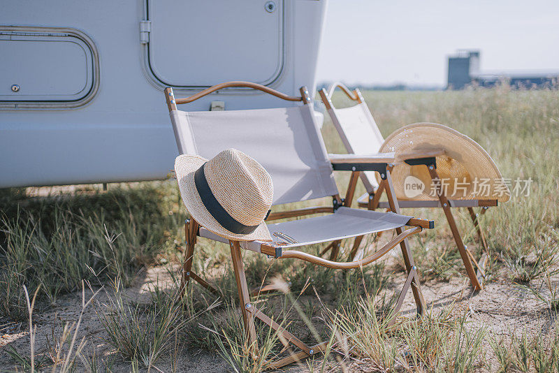 带草帽太阳镜的露营椅在稻田边的露营车旁