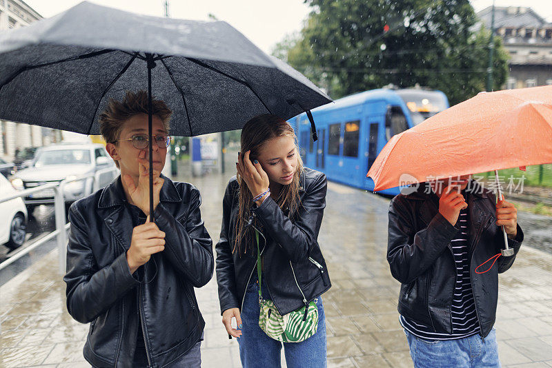 三个少年在一个雨天走在城市里