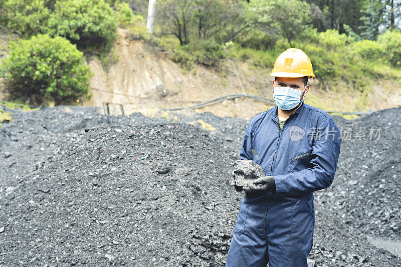 一名矿工在矿井中捧着一块煤的肖像。