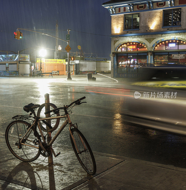 在瓢泼大雨的夜晚，在纽约布鲁克林科尼岛的街道上骑自行车。