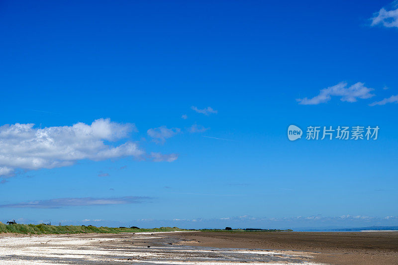 在一个阳光明媚的夏日，退潮时无人的海滩