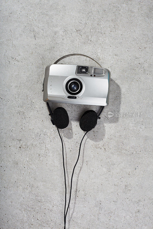 混凝土上的银色点拍相机和耳机。青春文化复古复兴项目