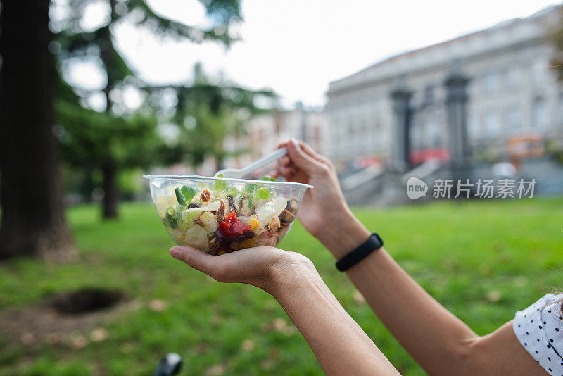 面目全非的女人拿着一个装着新鲜沙拉的塑料盒子