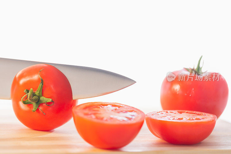一把刀在切西红柿，一个西红柿切成两半，一个西红柿整的