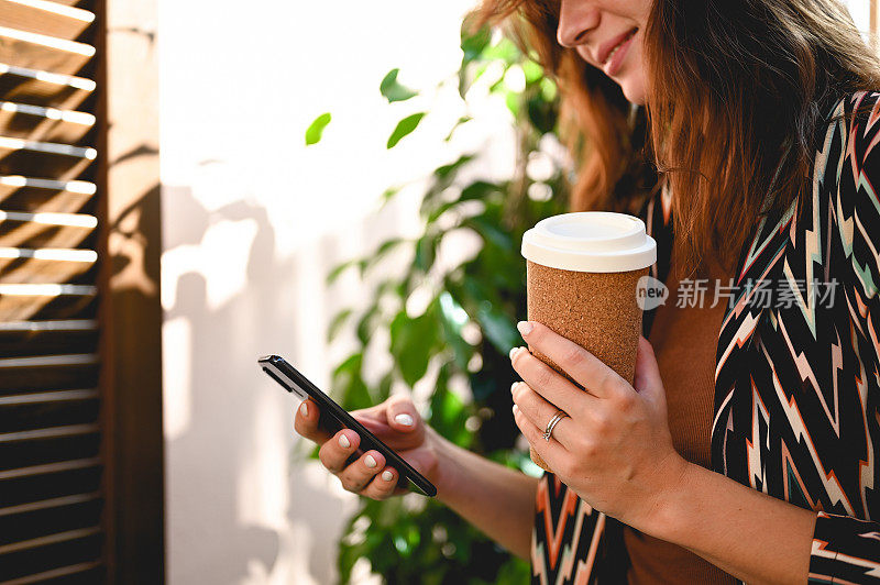 女子用一次性杯子喝咖啡，用智能手机。