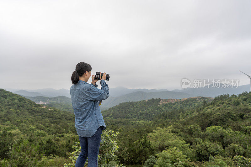 一位女摄影师在野外用相机拍照