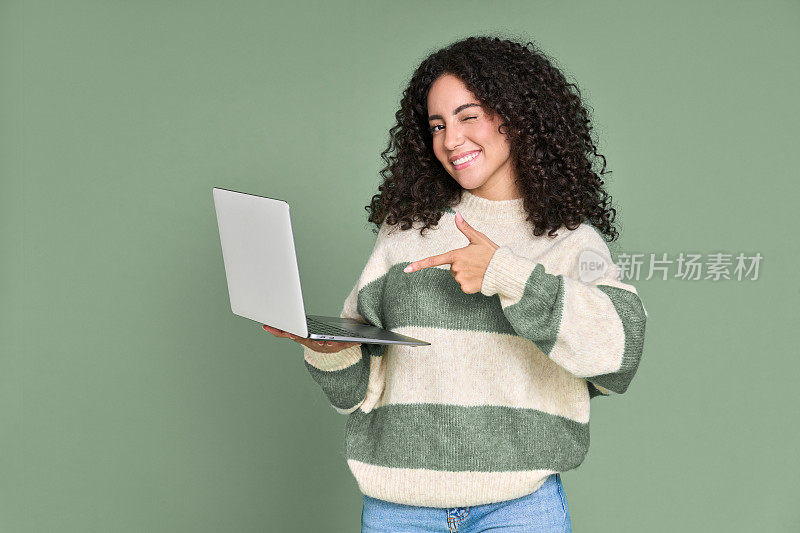年轻快乐兴奋的拉丁女人指着笔记本电脑孤立的绿色。