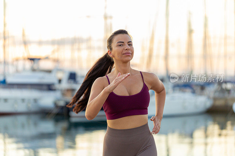 快乐健康的女人穿着运动服，在海边慢跑