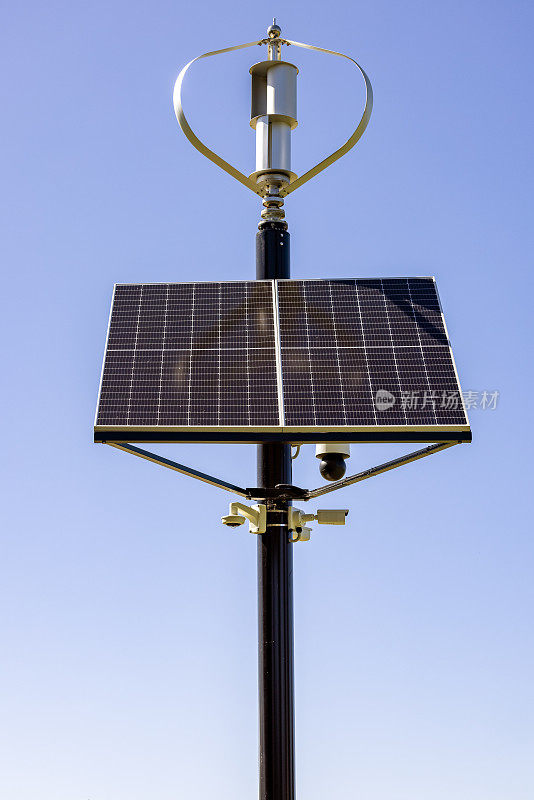 小型太阳能电池板与风力发电机，正面视图，蓝天背景与复制空间
