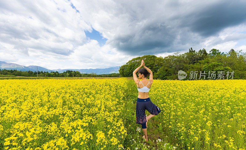 一位女士在黄色的油菜花地里练习瑜伽，放松身心