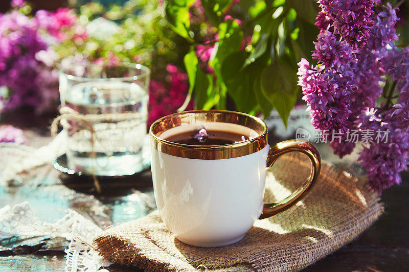 在丁香花丛中喝杯咖啡。美丽的小屋核心生活方式在阳光明媚的日子