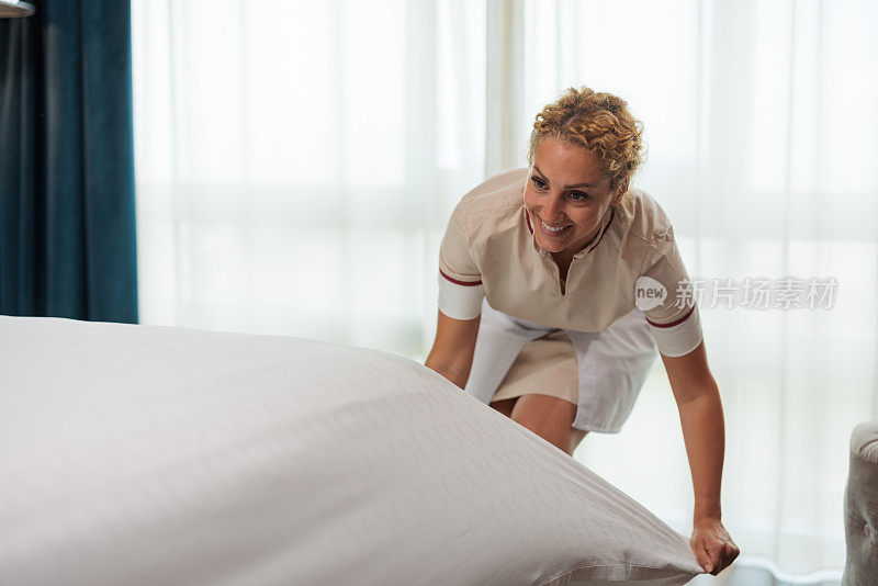 快乐的白人旅馆女服务员在整理床单