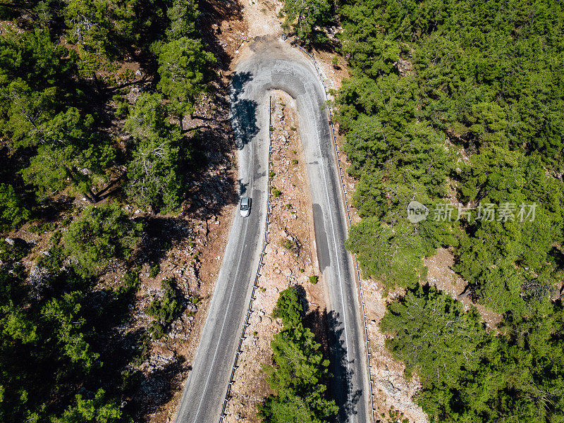 在森林山区的道路上行驶的车辆用无人机拍摄沥青弯道