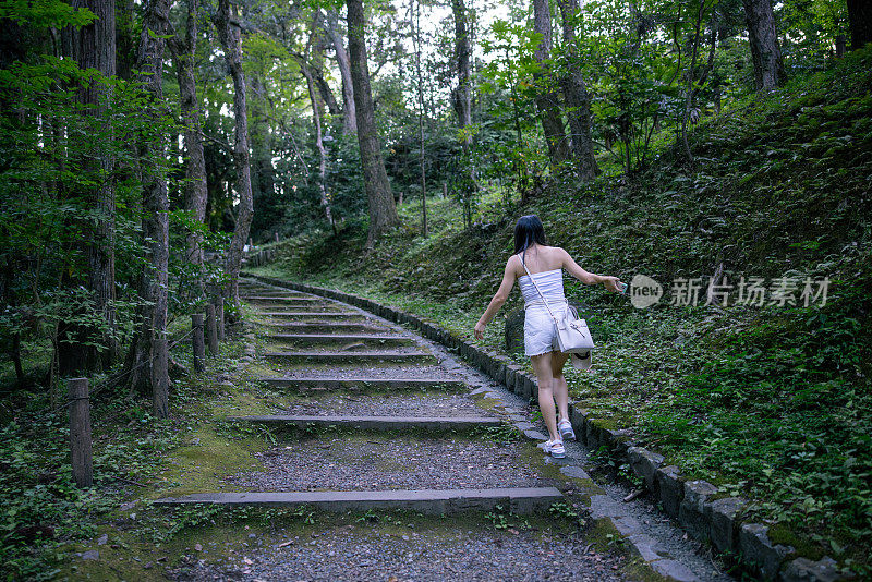 年轻女子在大自然中走上台阶的后视图