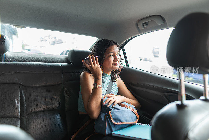 女乘客在汽车后座使用智能手机