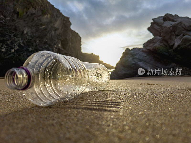 在葡萄牙的沙滩上，一个装满垃圾的空塑料瓶被疏忽地遗忘了