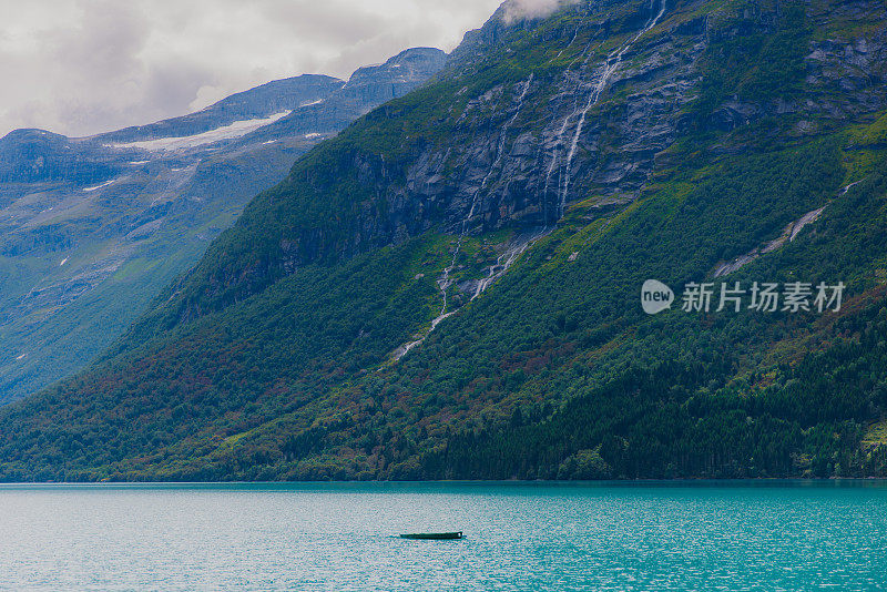 田园诗般的夏季景观与船在水晶蓝湖与山景在挪威