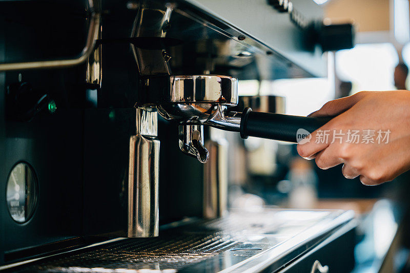 咖啡机在咖啡馆煮新鲜美味的浓缩咖啡。一步一步教你如何制作美味的咖啡。机器手握手柄的特写，专业的咖啡制作过程。
