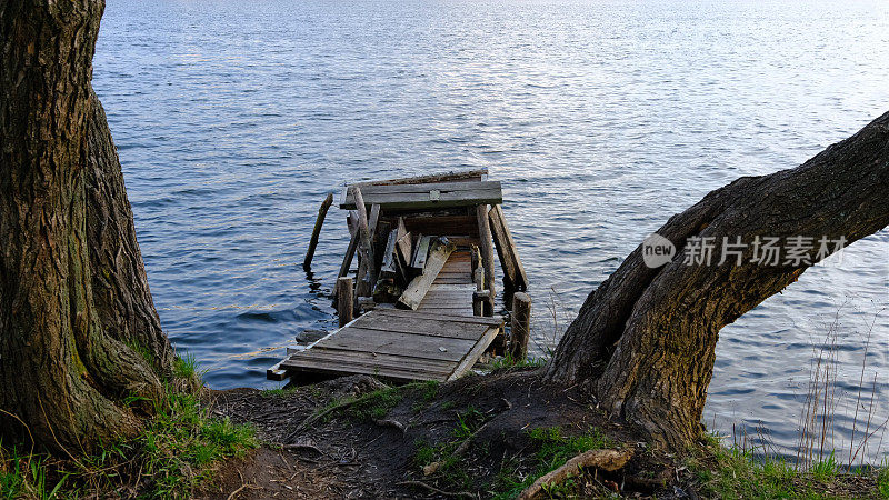 秋景——湖水和毁坏的木码头。秋天，森林里的湖上，老旧的烂木码头，缺了木板，有长凳。