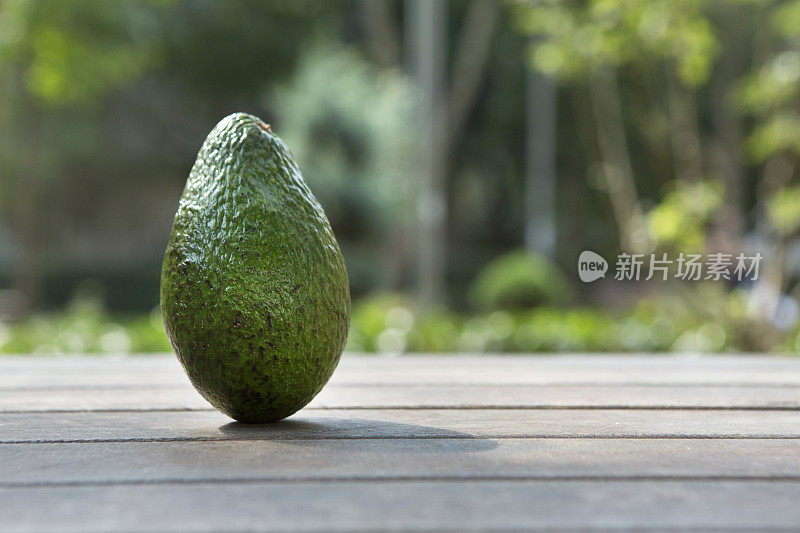 公园里的木桌上放牛油果。水果和蔬菜概念。